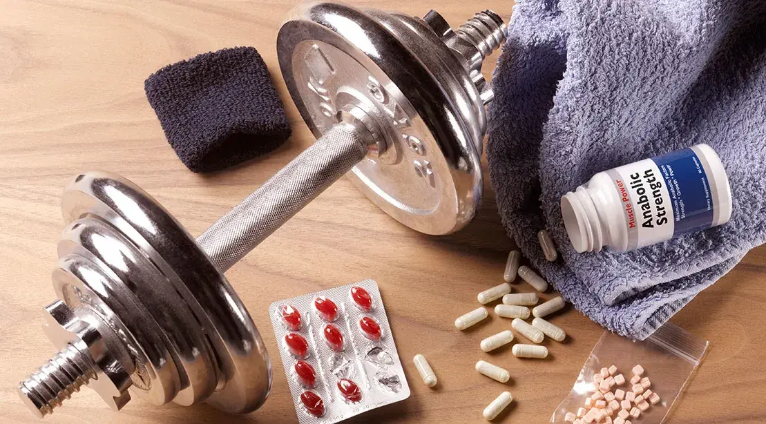 a dumbbell and pills next to a towel